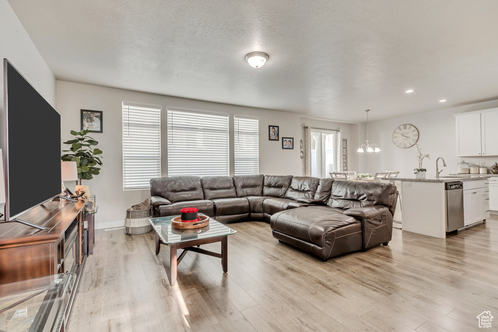 Living room with light hardwood / wood-style flooring, a textured ceiling, a chandelier, and plenty of natural light