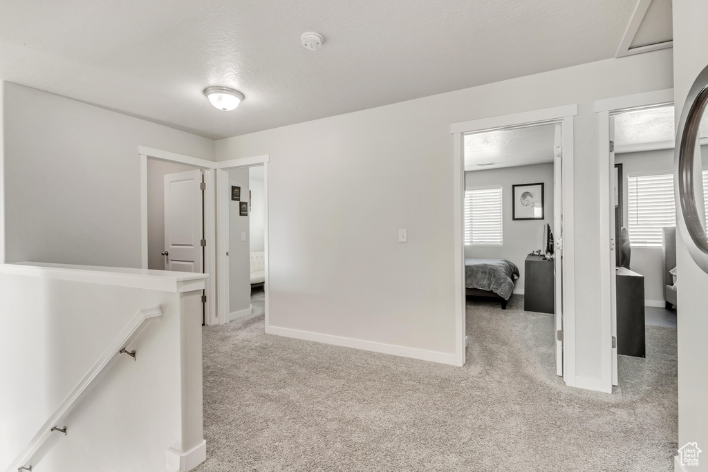 Hall featuring light carpet and a textured ceiling