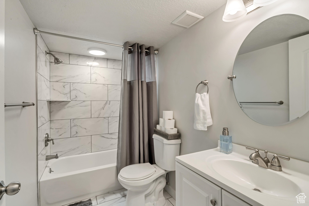 Full bathroom featuring vanity, shower / tub combo with curtain, and toilet