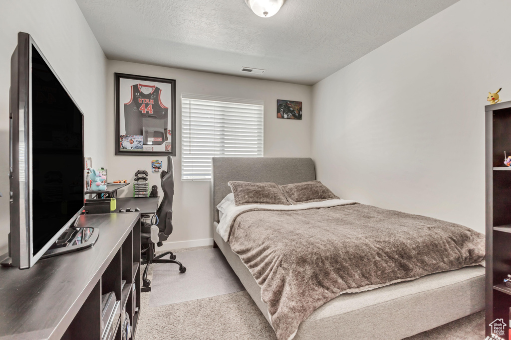 Bedroom with a textured ceiling and light colored carpet