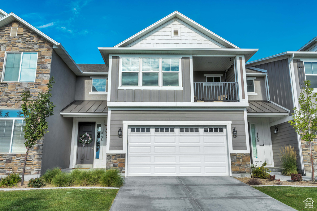 View of front facade with a front yard, a balcony, and a garage