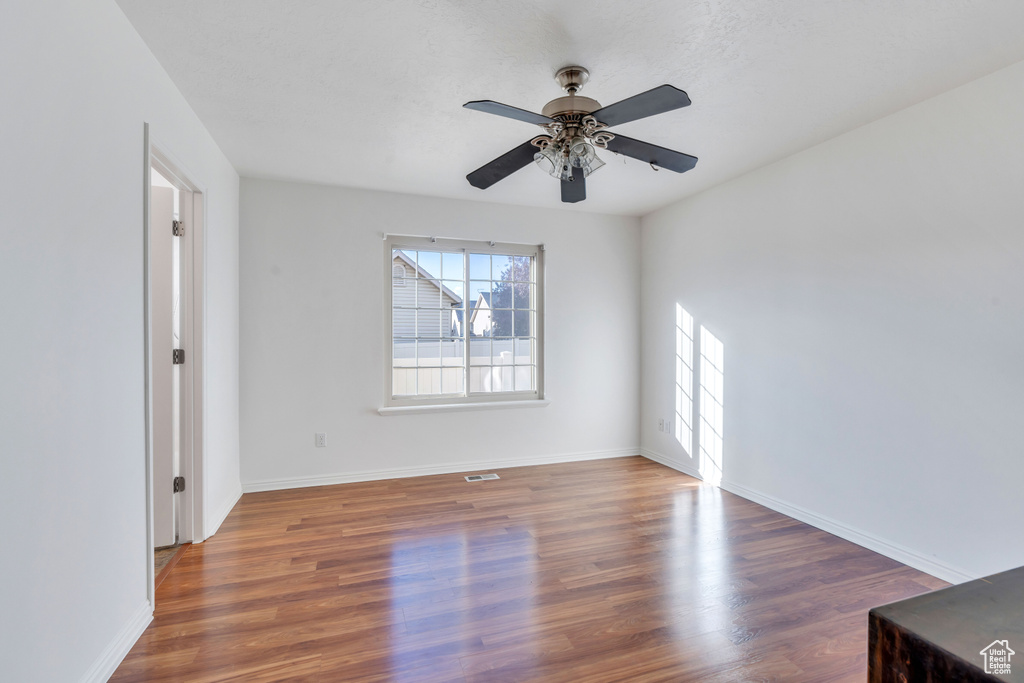 Empty room with ceiling fan and dark hardwood / wood-style floors