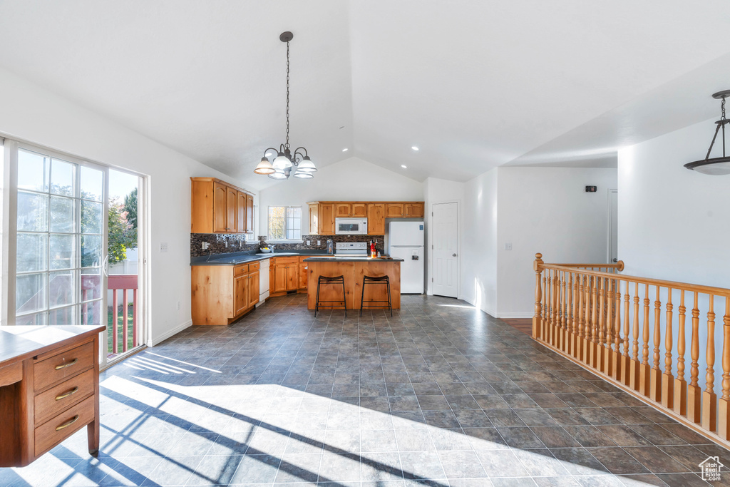 Kitchen with lofted ceiling, white appliances, decorative light fixtures, and a kitchen island