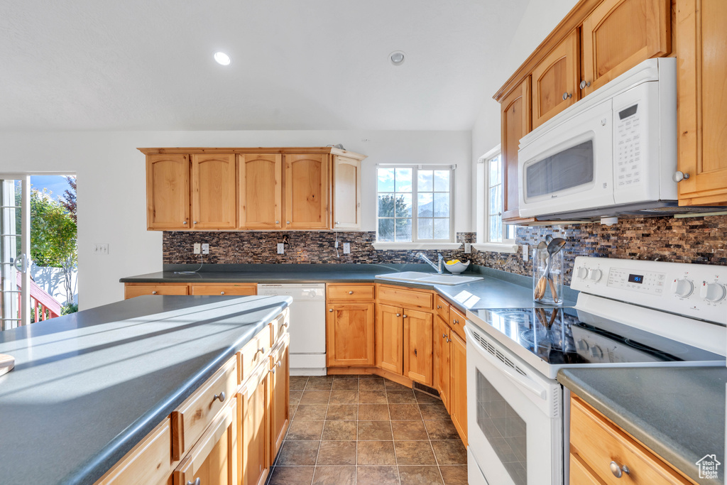 Kitchen with a healthy amount of sunlight, sink, white appliances, and tasteful backsplash