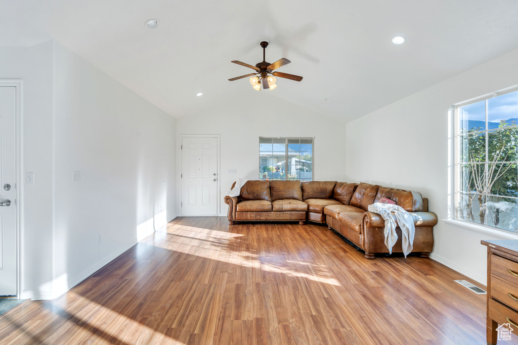 Living room with light hardwood / wood-style floors, lofted ceiling, and ceiling fan