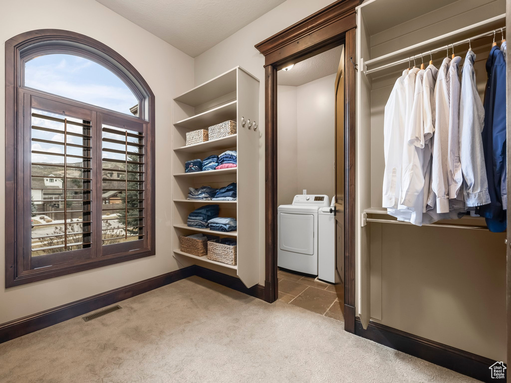 Walk in closet with washing machine and dryer and light colored carpet