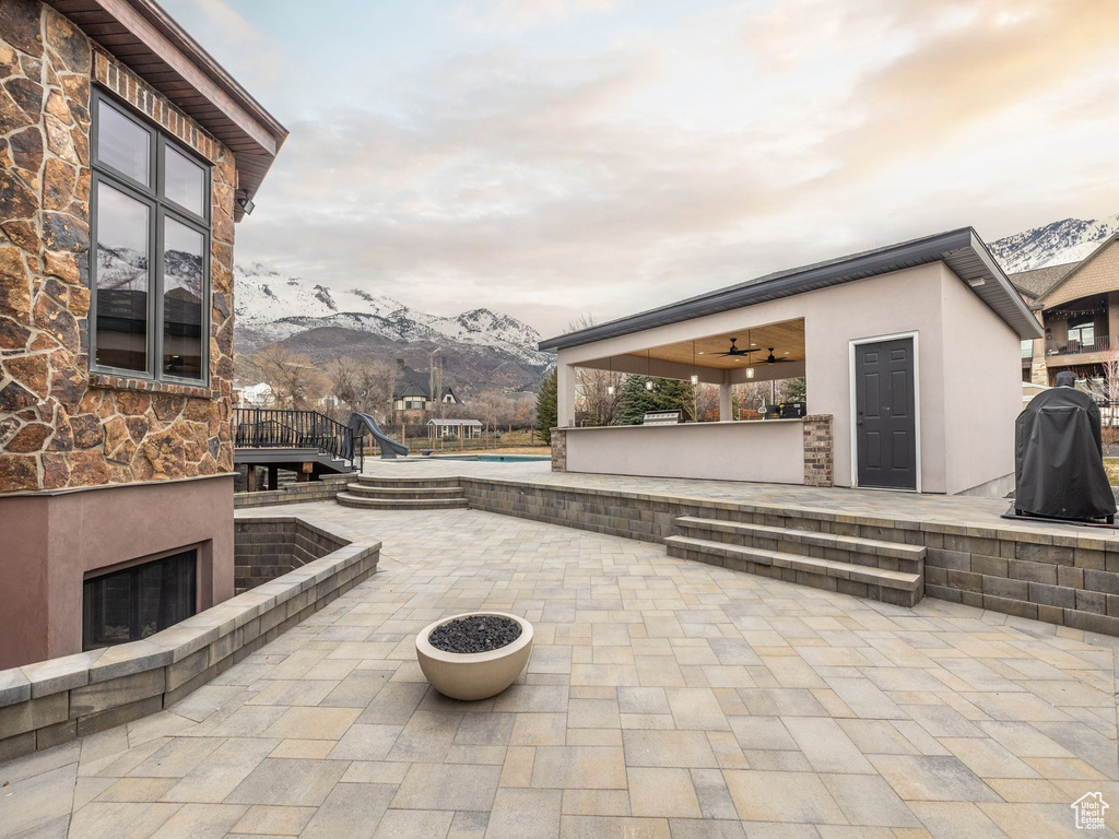 View of patio with a mountain view, exterior fireplace, and ceiling fan