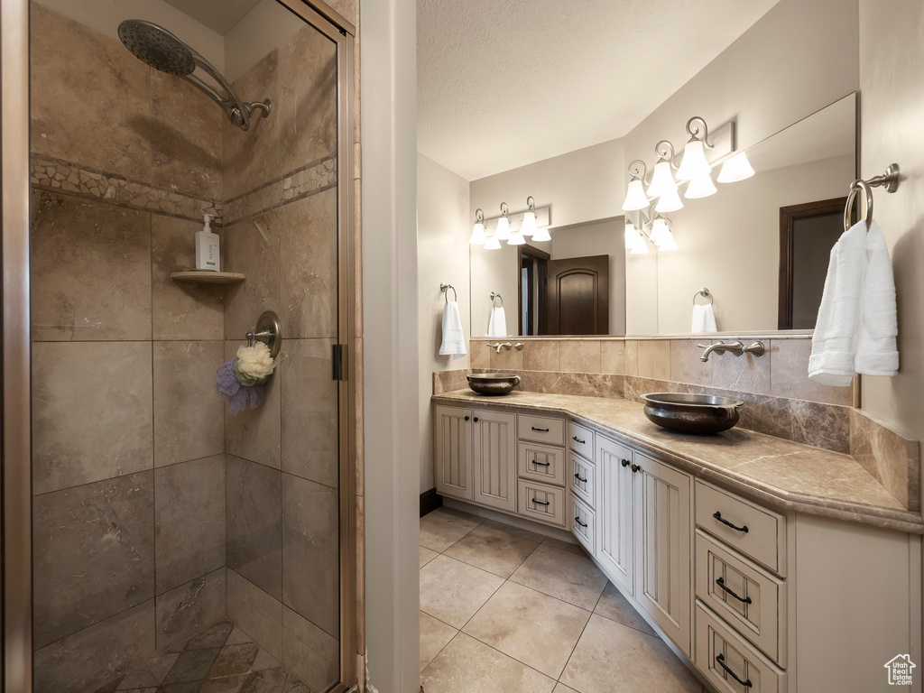 Bathroom with vanity, a textured ceiling, tile patterned floors, and a shower with shower door