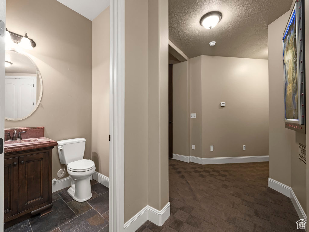 Bathroom with vanity, a textured ceiling, and toilet