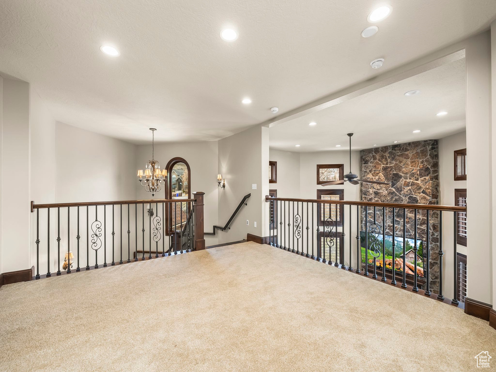 Hall with an inviting chandelier and carpet flooring