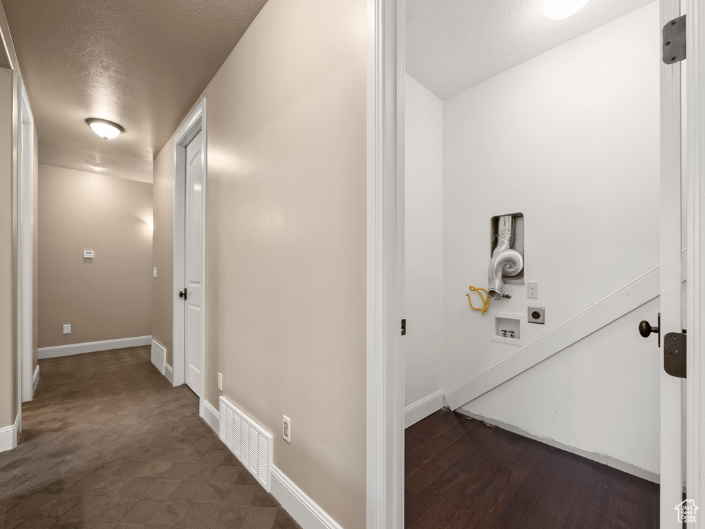 Hall featuring a textured ceiling and dark hardwood / wood-style floors