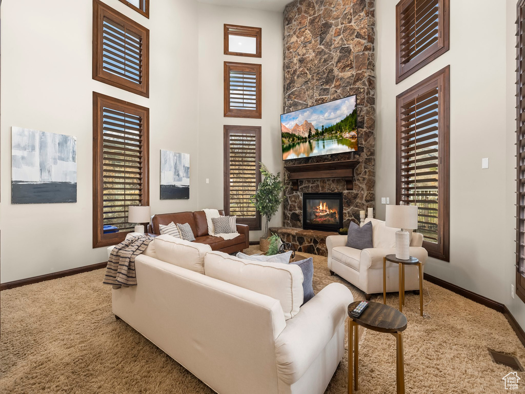 Living room with carpet, a stone fireplace, and a towering ceiling