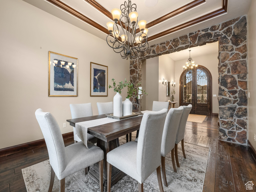 Dining room featuring dark wood-type flooring, a notable chandelier, and a tray ceiling