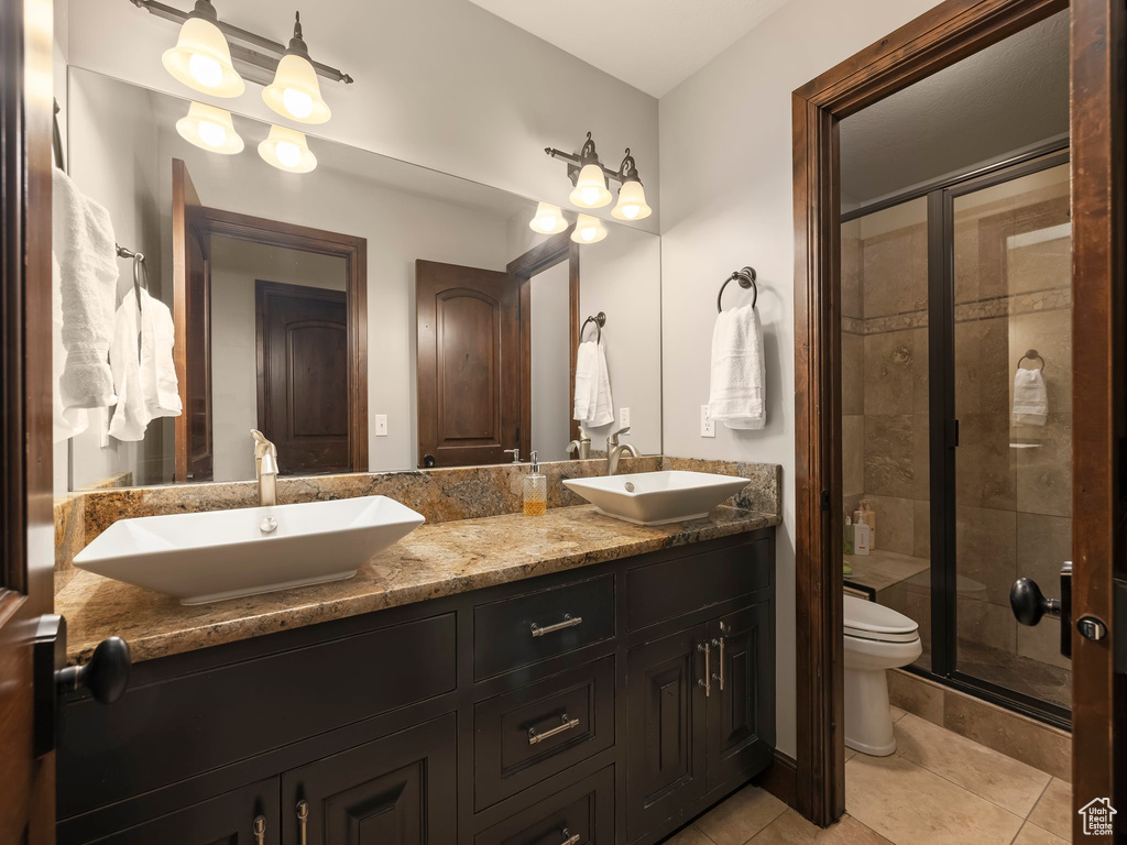 Bathroom featuring vanity, tile patterned flooring, toilet, and an enclosed shower