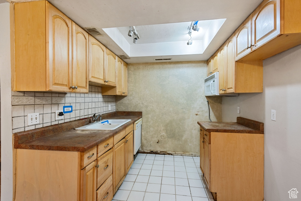 Kitchen with white appliances, tasteful backsplash, light tile patterned flooring, sink, and rail lighting