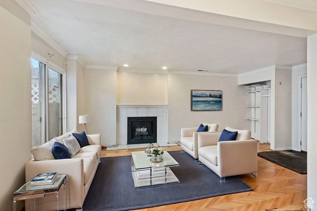 Living room featuring light parquet flooring, ornamental molding, and a fireplace