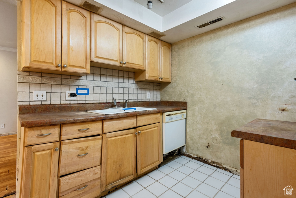 Kitchen featuring sink, dishwasher, backsplash, light tile patterned floors, and light brown cabinets