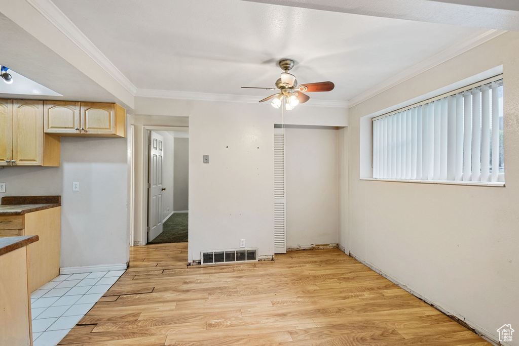 Interior space featuring light hardwood / wood-style floors, crown molding, light brown cabinetry, and ceiling fan