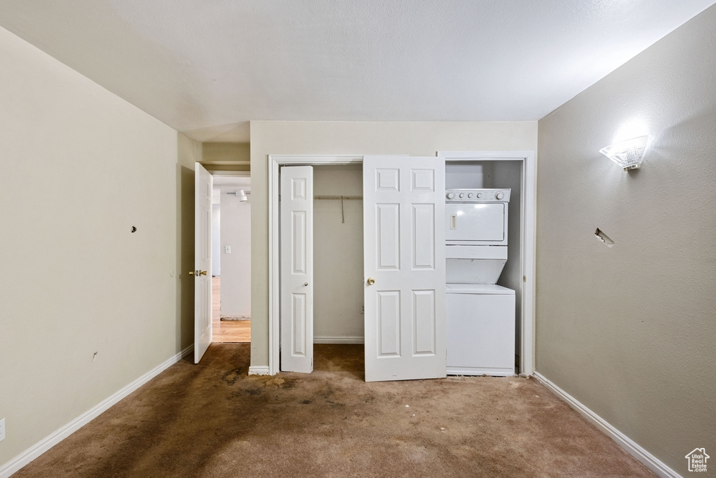 Unfurnished bedroom with carpet floors and stacked washer and clothes dryer