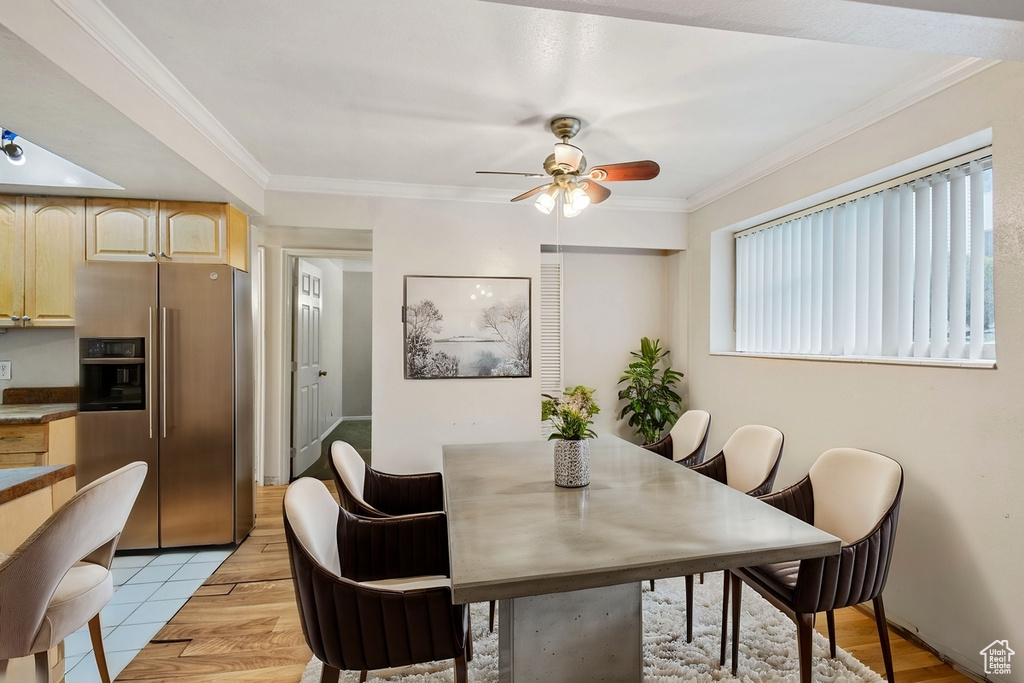 Dining area with crown molding, light tile patterned floors, and ceiling fan