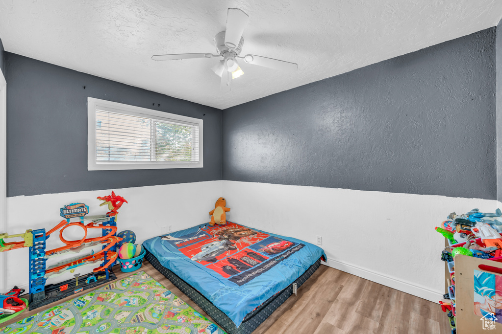 Bedroom with ceiling fan, a textured ceiling, and hardwood / wood-style floors