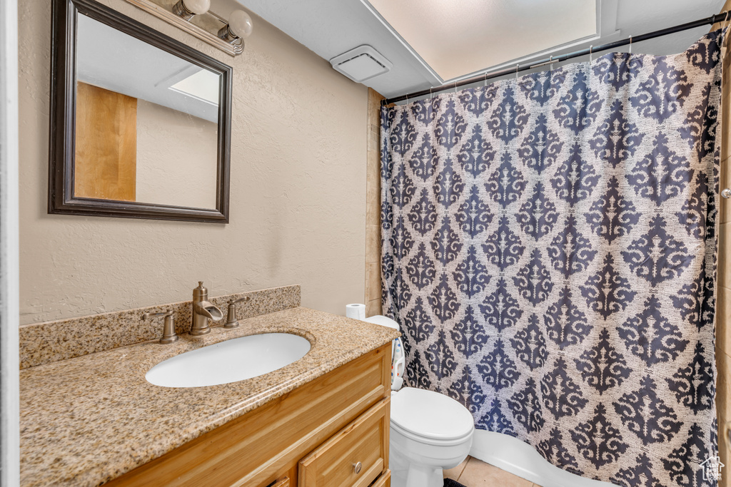 Bathroom featuring vanity, curtained shower, toilet, and tile patterned flooring
