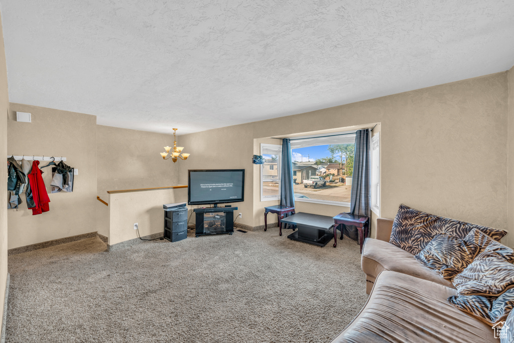 Living room featuring carpet floors, a chandelier, and a textured ceiling