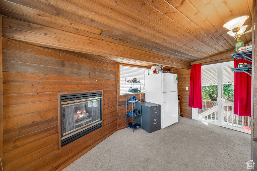 Interior space with lofted ceiling, wooden walls, wood ceiling, and carpet
