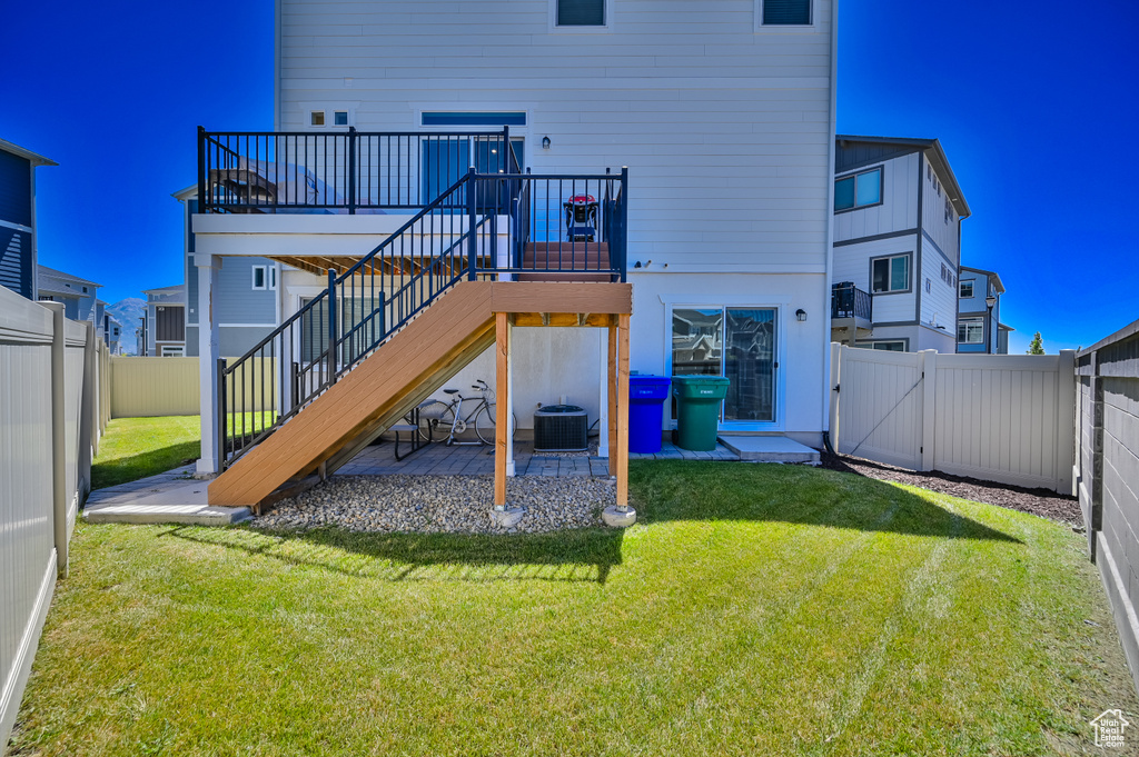 Back of property featuring central AC, a yard, a deck, and a patio