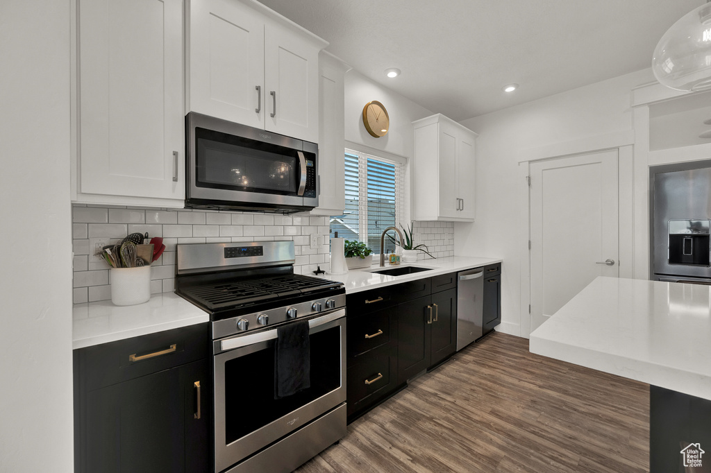 Kitchen featuring tasteful backsplash, appliances with stainless steel finishes, sink, white cabinets, and dark hardwood / wood-style floors