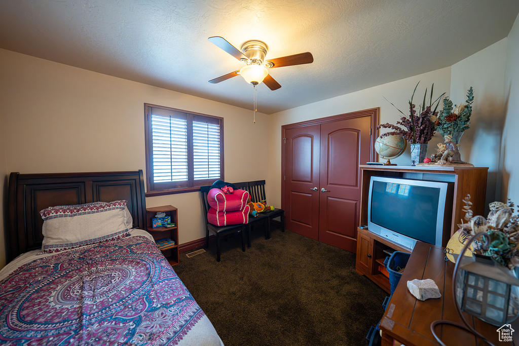 Carpeted bedroom featuring a closet, a textured ceiling, and ceiling fan