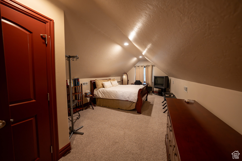 Carpeted bedroom with vaulted ceiling and a textured ceiling