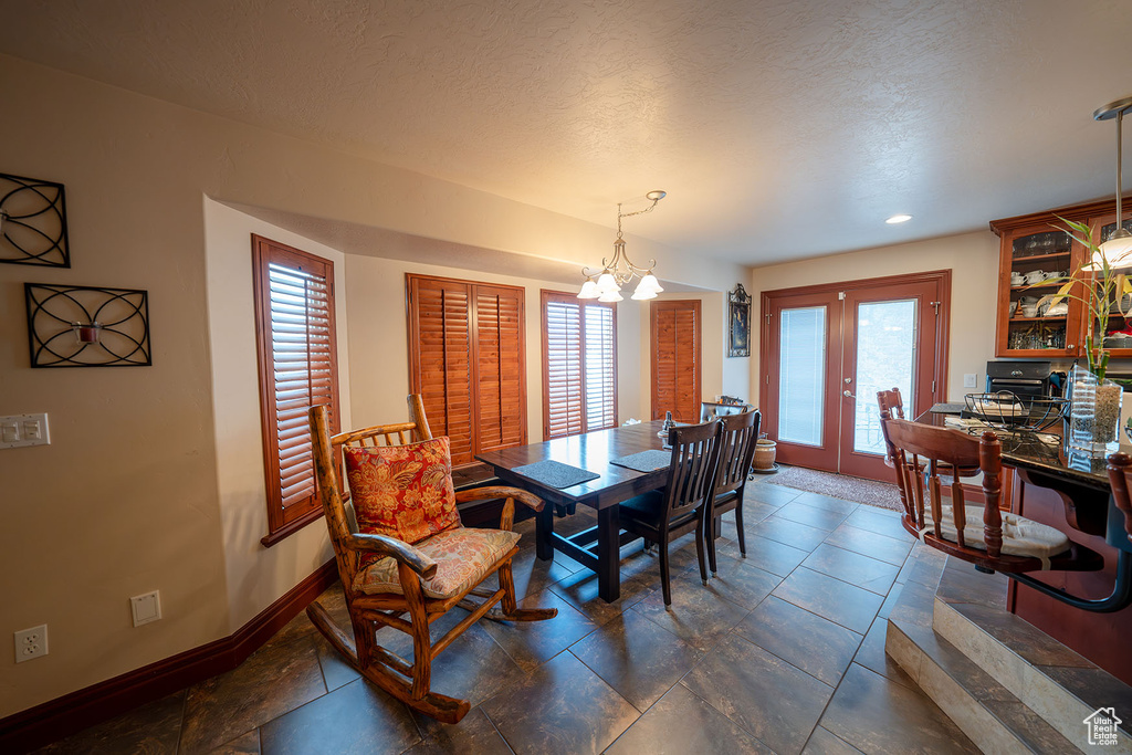 Dining room with french doors, a textured ceiling, and a notable chandelier