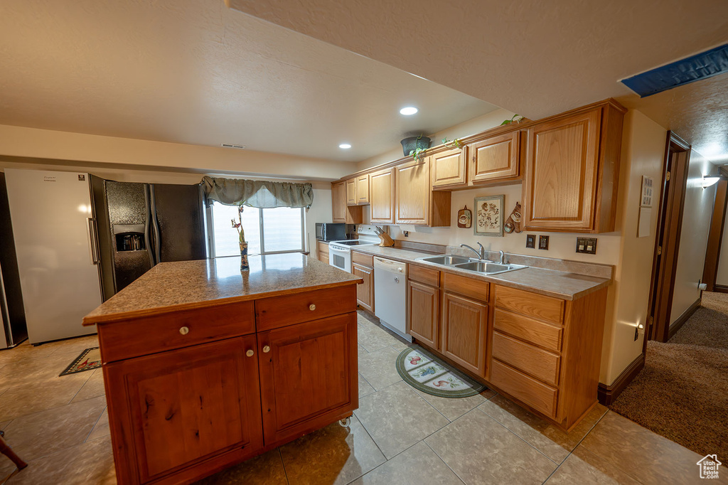 Kitchen with white appliances, light tile patterned floors, sink, and a kitchen island