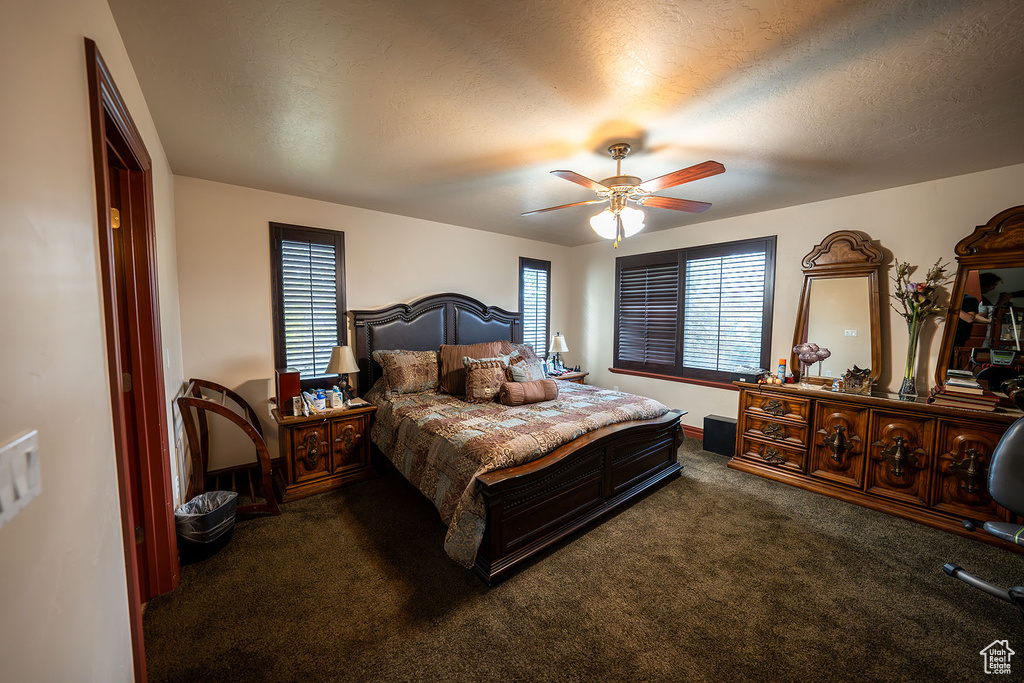 Carpeted bedroom featuring a textured ceiling and ceiling fan