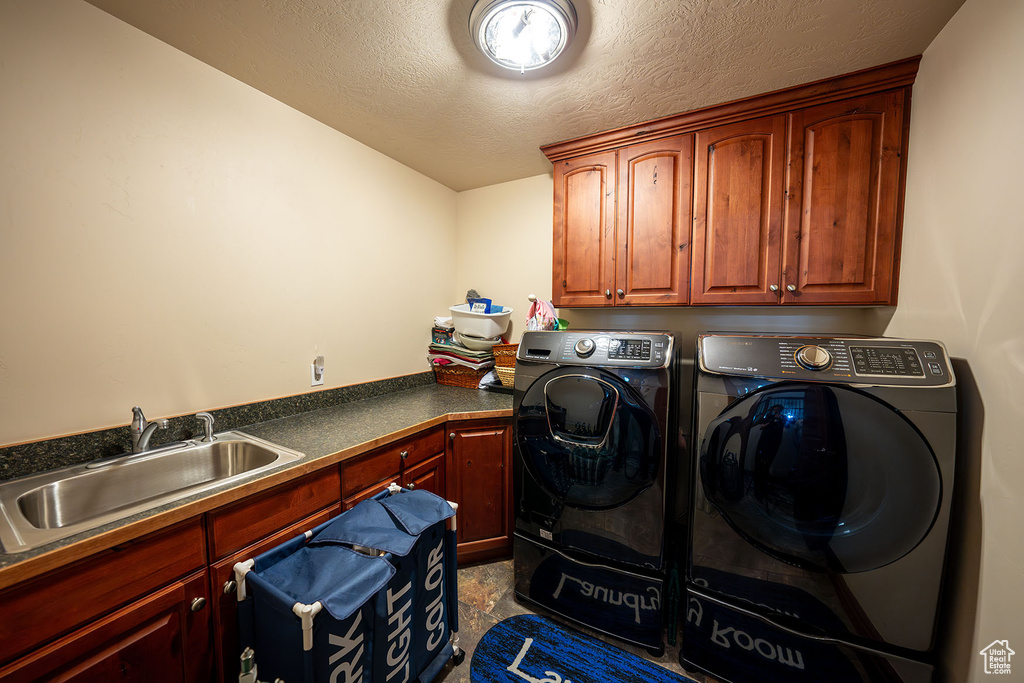 Laundry room with sink, independent washer and dryer, a textured ceiling, and cabinets