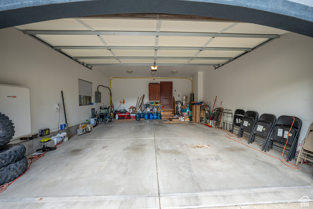 Garage featuring a garage door opener, electric panel, and refrigerator