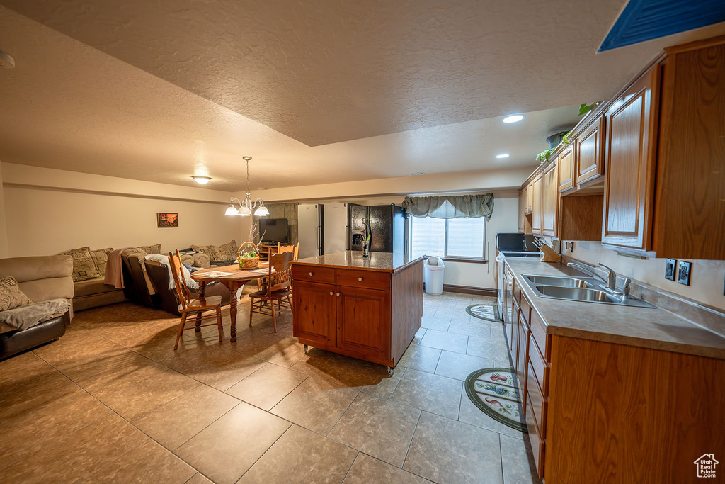 Kitchen featuring hanging light fixtures, sink, light tile patterned flooring, a notable chandelier, and a textured ceiling