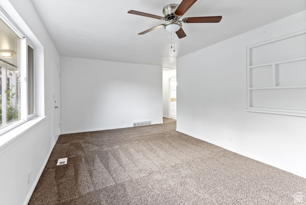 Carpeted empty room with ceiling fan