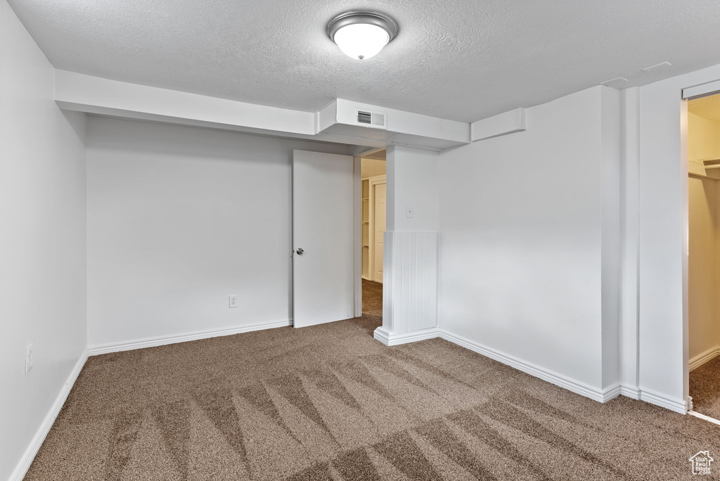 Basement featuring a textured ceiling and dark carpet