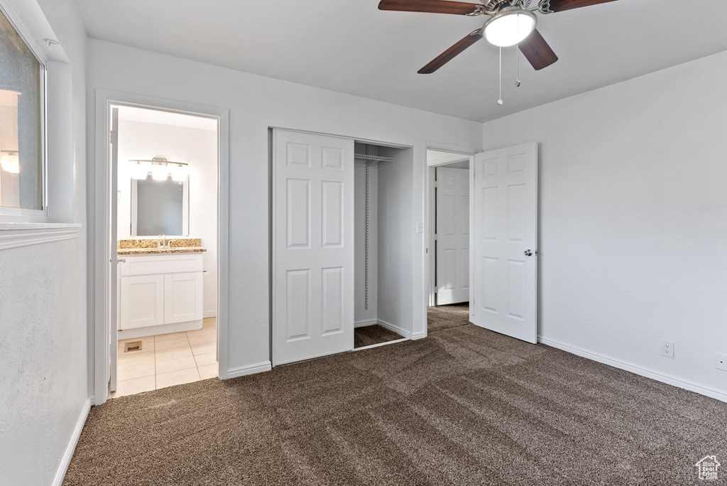 Unfurnished bedroom with ensuite bathroom, sink, a closet, ceiling fan, and dark carpet