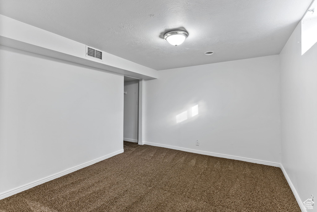 Basement featuring a textured ceiling and dark colored carpet