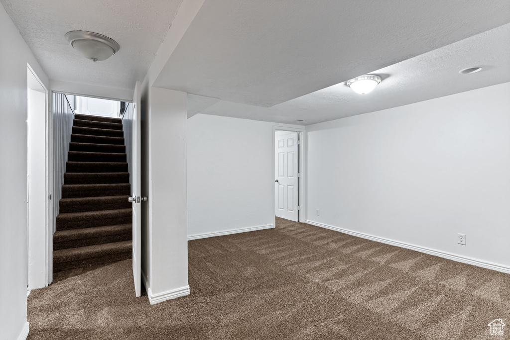 Basement featuring a textured ceiling and dark carpet