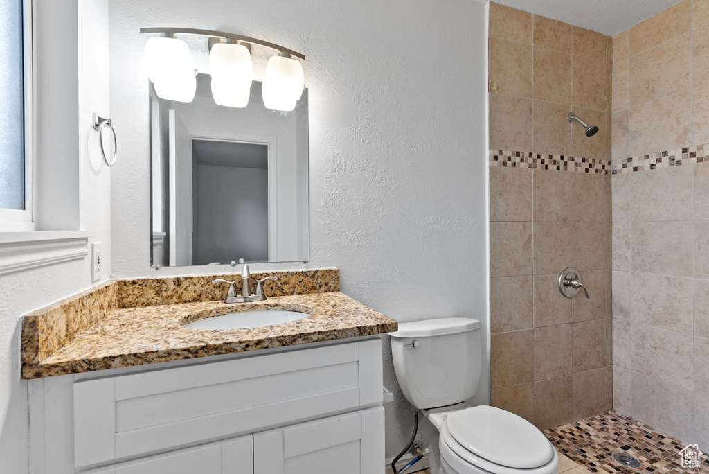 Bathroom featuring vanity, toilet, and tiled shower