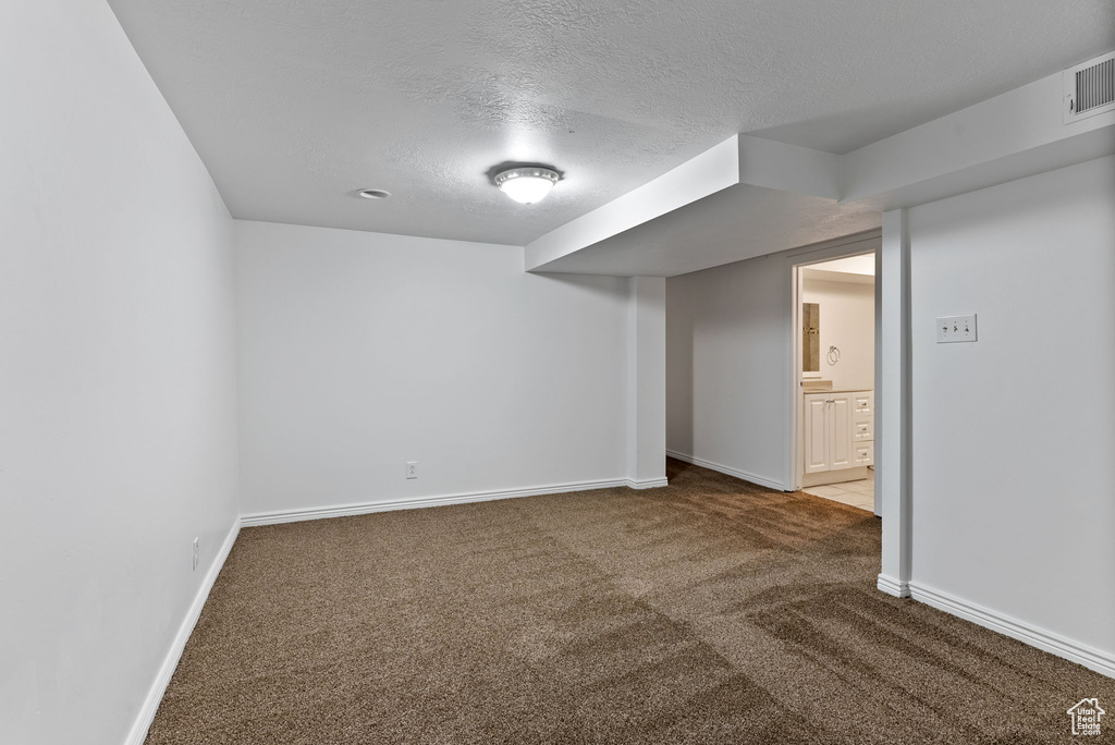 Unfurnished room featuring a textured ceiling and carpet floors