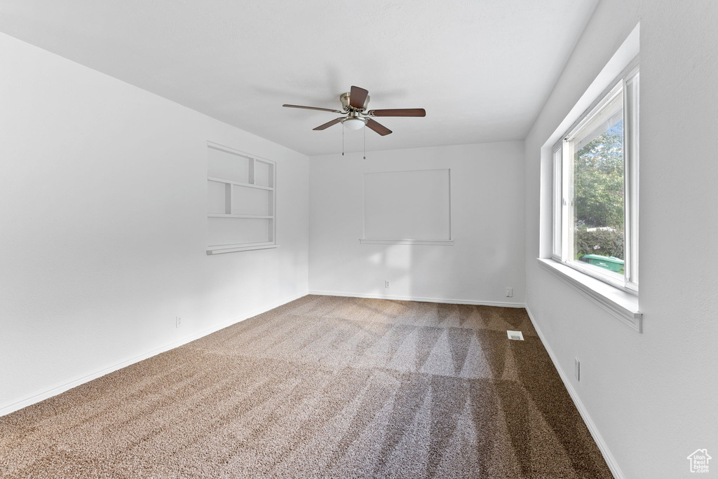 Spare room featuring carpet and ceiling fan