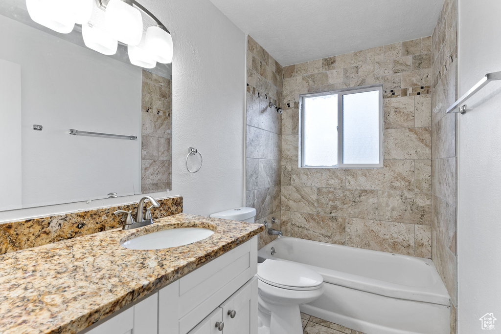 Full bathroom featuring vanity, tiled shower / bath combo, toilet, and tile patterned floors