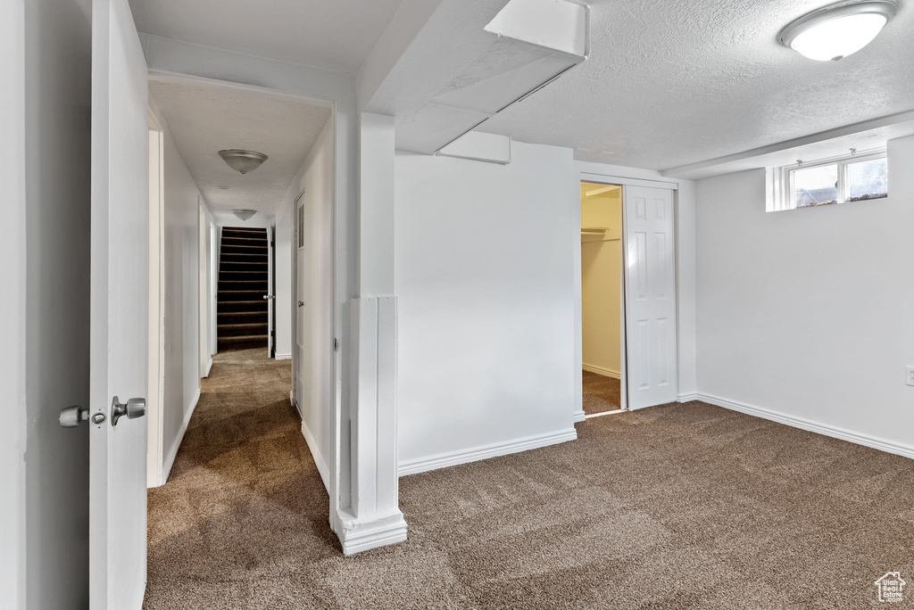 Interior space with dark carpet and a textured ceiling