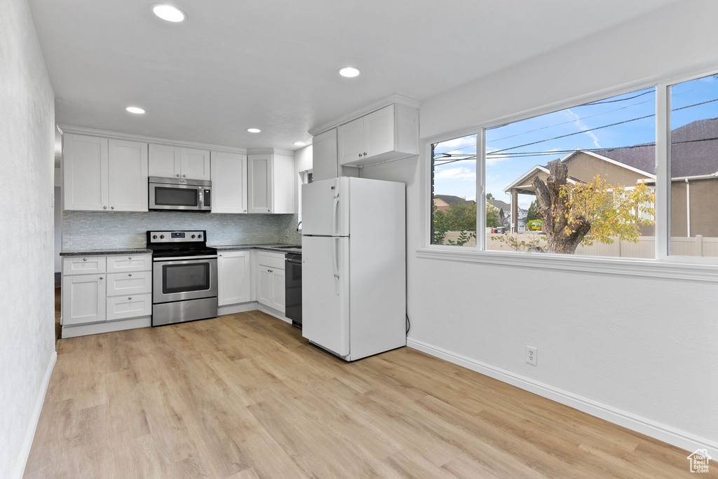 Kitchen featuring white cabinetry, light hardwood / wood-style floors, appliances with stainless steel finishes, and decorative backsplash