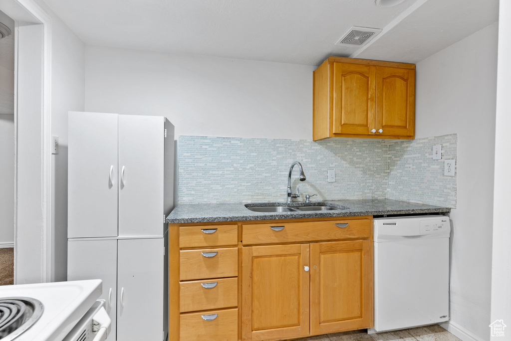 Kitchen featuring sink, dishwasher, decorative backsplash, and light stone counters